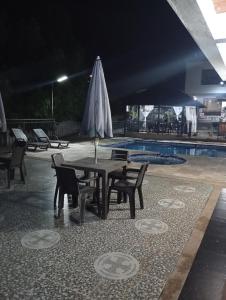 een tafel en stoelen naast een zwembad met een parasol bij Narü extremo in Utica