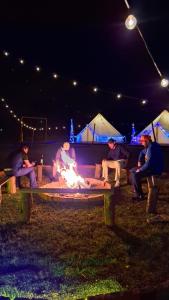 Eine Gruppe von Menschen, die nachts um ein Feuer herum sitzen in der Unterkunft Rondo Glamping By GEstores in Pátzcuaro