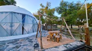 Jurte mit einem Tisch und Stühlen auf einer Holzterrasse in der Unterkunft Rondo Glamping By GEstores in Pátzcuaro