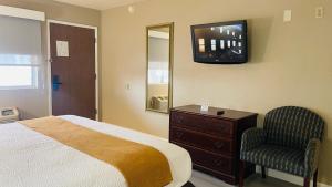 a bedroom with a bed and a tv and a chair at Rodeway Inn Jackson in Jackson