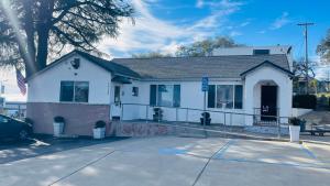 a white house with a tree in front of it at Rodeway Inn Jackson in Jackson