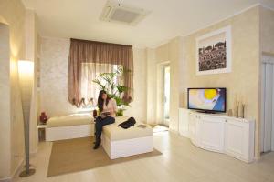 a woman sitting on a couch in a living room at Hotel C'era Una Volta in Castiglione della Pescaia