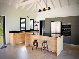a kitchen with a large island with two bar stools at Maison dans la Forêt avec vue mer accès rivière in Goyave +12 photos