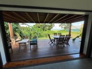 a view of a deck with a table and chairs at Maison dans la Forêt avec vue mer accès rivière in Goyave