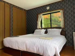 a bedroom with a large white bed with a window at 箱根宿燕帰 in Hakone