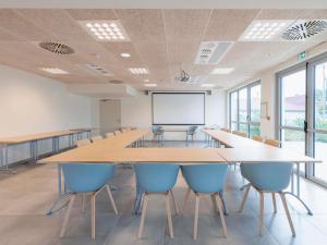 une grande salle de conférence avec une grande table et des chaises dans l'établissement Hotel ibis Mont De Marsan, à Mont-de-Marsan