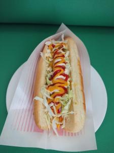 un hot-dog dans un emballage en papier sur une assiette dans l'établissement Big Tree JUDO ハウス, à Urazoe