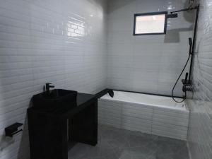 een witte badkamer met een bad en een wastafel bij Bumi Geulis Hotel & Residence in Sukabumi