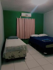 een kamer met 2 bedden en een groene muur bij Pousada Andrade in Parnaíba