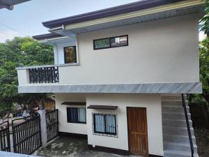 a white house with a balcony and a door at Teachers Home in Panong +5 photos