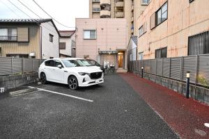 a white car parked in a parking lot at 民泊 Ichinomiya K Room 1A in Ichinomiya