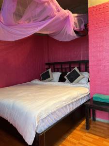 a bedroom with a bed with a pink wall at Chi Homestay in Sapa