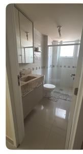 a white bathroom with a sink and a toilet at Rua 220 in Itapema
