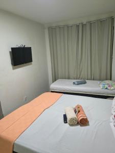 Twee bedden in een kamer met handdoeken en een tv. bij Casa espaçosa para 8 hóspedes in Volta Redonda