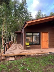 una casa con un ponte e una sedia gialla sopra di Cabaña Los Arrayanes 2 a Coihueco