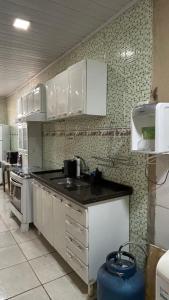 a kitchen with white cabinets and a sink at Casa Aconchegante Uberlândia in Uberlândia
