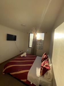 una camera con un letto con una coperta rossa e bianca di Departamento tauro a Santiago