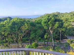 a fence with trees and the ocean in the background at Hilltop Cottage in Cabulihan
