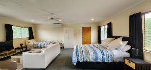 une chambre avec un lit, un canapé et une télévision dans l'établissement Avocado Orchard Retreat!, à Katikati