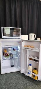 a white refrigerator with its door open and a microwave at Avocado Orchard Retreat! in Katikati