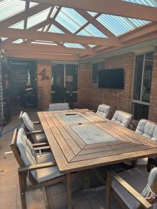 een grote houten tafel met stoelen en een televisie bij Echucas Pawfect Accommodation - Dog Friendly in Echuca