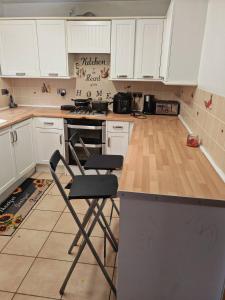 eine Küche mit weißen Schränken, einer Theke und einem Stuhl in der Unterkunft Relax in this Charming Rushden Retreat in Rushden + 7 Fotos