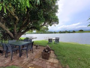 een picknicktafel en stoelen naast een meer bij Tweed River Waterfront Cottage in Murwillumbah