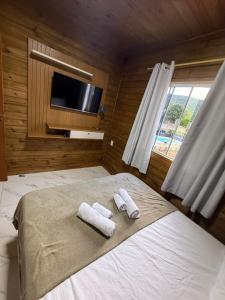 een slaapkamer met 2 handdoeken op een bed en een tv bij Casa Aconchego in Florianópolis