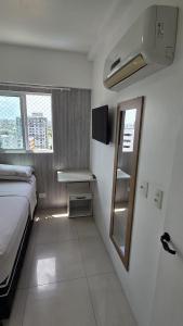 een kleine kamer met een bed en een spiegel bij Morada Pio IX in Recife