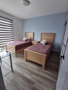 two beds in a room with violet sheets at Cielito Lindo in Uruapan del Progreso