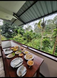 een tafel met borden eten erop met een raam bij Tea Brook Lodge Ella in Ella