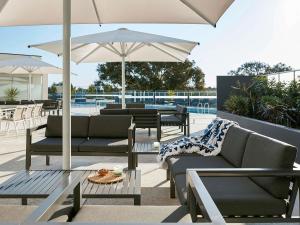 een patio met stoelen en tafels en een parasol bij Art Series - The Watson in Adelaide