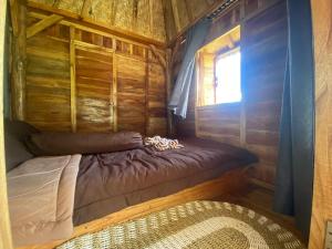 ein kleines Bett in einer Holzhütte mit einem Fenster in der Unterkunft Batur Twin house in Kubupenlokan