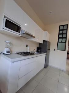 een witte keuken met een fornuis en een magnetron bij Monarca in Uruapan del Progreso +2 foto's