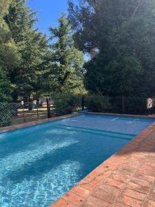 a blue swimming pool with trees and a fence at Rocio de Luna in Villa Ventana