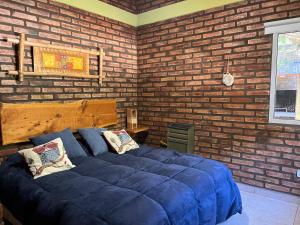 a bedroom with a large blue bed in a brick wall at Rocio de Luna in Villa Ventana