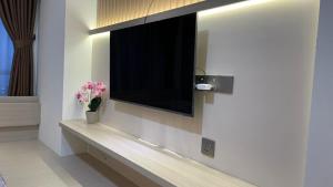 a television on a wall in a room with flowers at Dewi's Pollux in Batam Center