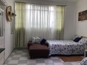 a bedroom with a bed and a chair and a window at Entire accommodation Departamento Mi Mexico in Mexico City