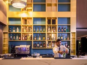 een man die achter een bar een drankje maakt bij Novotel Malta Sliema in Il-Gżira