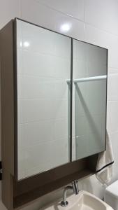 een badkamer met een glazen spiegel boven de wastafel bij Jardim dos Ipês in Araranguá +16 foto's