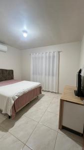 een slaapkamer met een bed en een televisie. bij Jardim dos Ipês in Araranguá