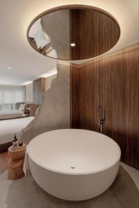 ein Bad mit einer weißen Badewanne und einem Bett in der Unterkunft The Cara Hotel in Kota Kinabalu