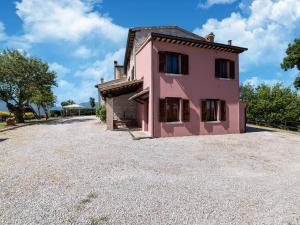 ein rosa Haus auf einer Kieseinfahrt in der Unterkunft Apartment in a farmhouse with 2 swimming pools in Cagli