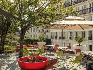 un patio extérieur avec tables, chaises et un parasol dans l'établissement Mercure Paris Montmartre Sacré Coeur, à Paris