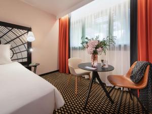 een hotelkamer met een tafel met een vaas met bloemen bij Mercure Paris Porte De Versailles Expo in Parijs