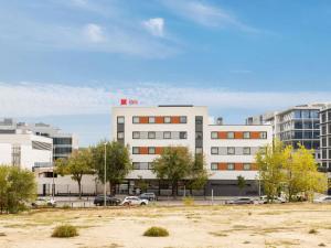 een wit gebouw met een parkeerplaats ervoor bij ibis Madrid Norte Las Tablas in Madrid