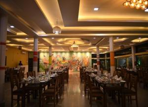 a banquet hall with long tables and chairs and a painting at Kumar Green Resort in Guwahati