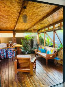 eine Veranda mit einem Sofa und Stühlen auf einem Holzdeck in der Unterkunft Fare Miriau in Papara