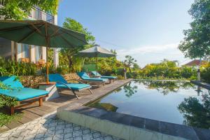 ein Pool mit Liegestühlen und Sonnenschirmen neben einem Gebäude in der Unterkunft Govardhan Nusa Penida in Nusa Penida