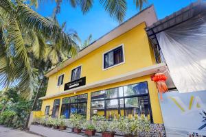 een geel gebouw met potplanten ervoor bij Townhouse Morjim in Goa +31 foto's